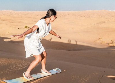 tourist enjoying dune bashing, sand surfing, camel rides and refreshments on a morning desert safari in dubai