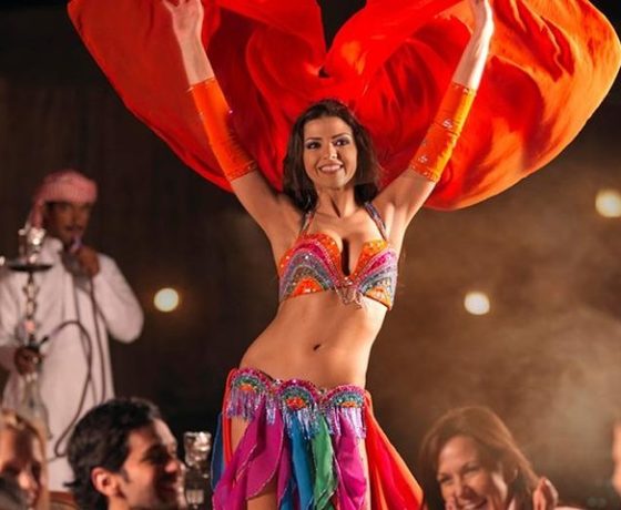 tourists enjoying the belly dance show, fire spinners, tanoura show and are enjoying the bbq buffet dinner on the best desert safari options in dubai