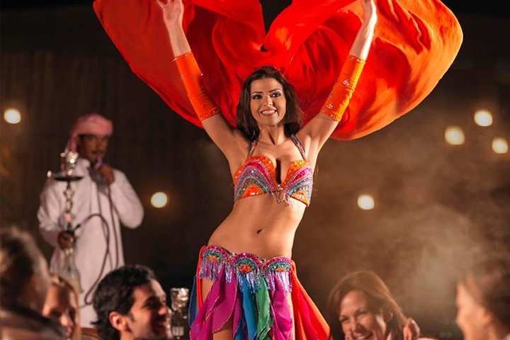 tourists enjoying the belly dance show, fire spinners, tanoura show and are enjoying the bbq buffet dinner on the best desert safari options in dubai